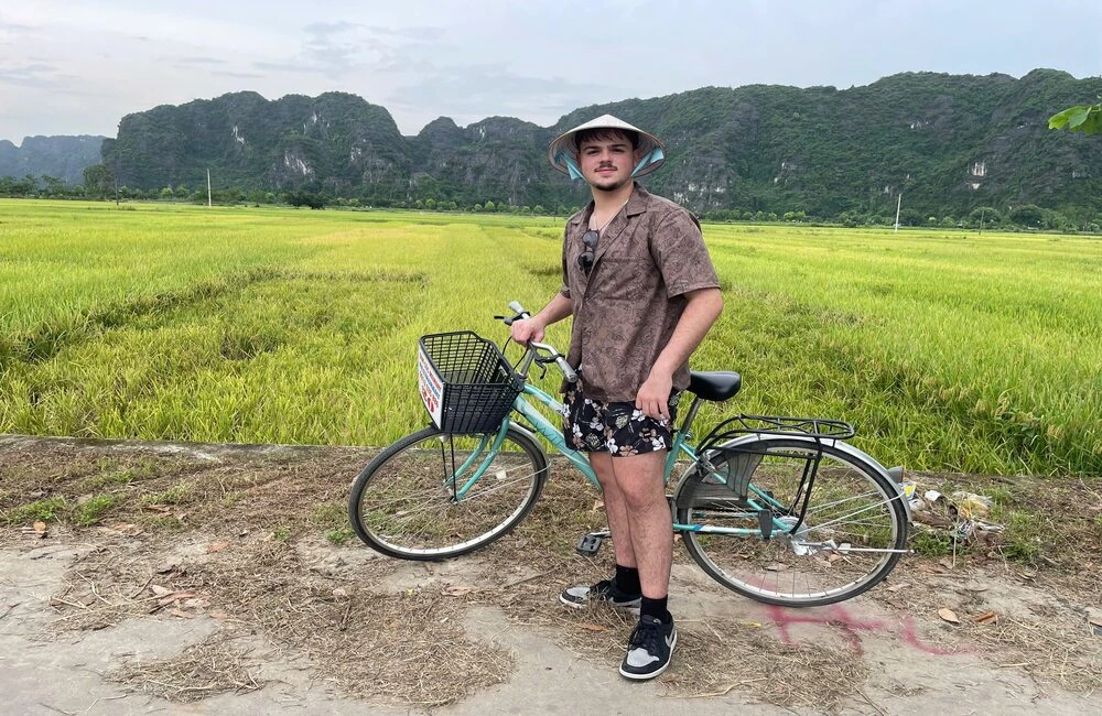 Travelers take photos next to golden Rice field during biking