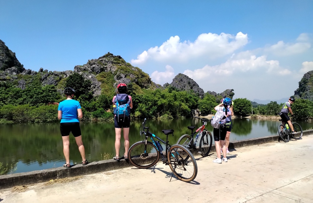 Travelers taking a break next to Ngo Dong river during a bike ride